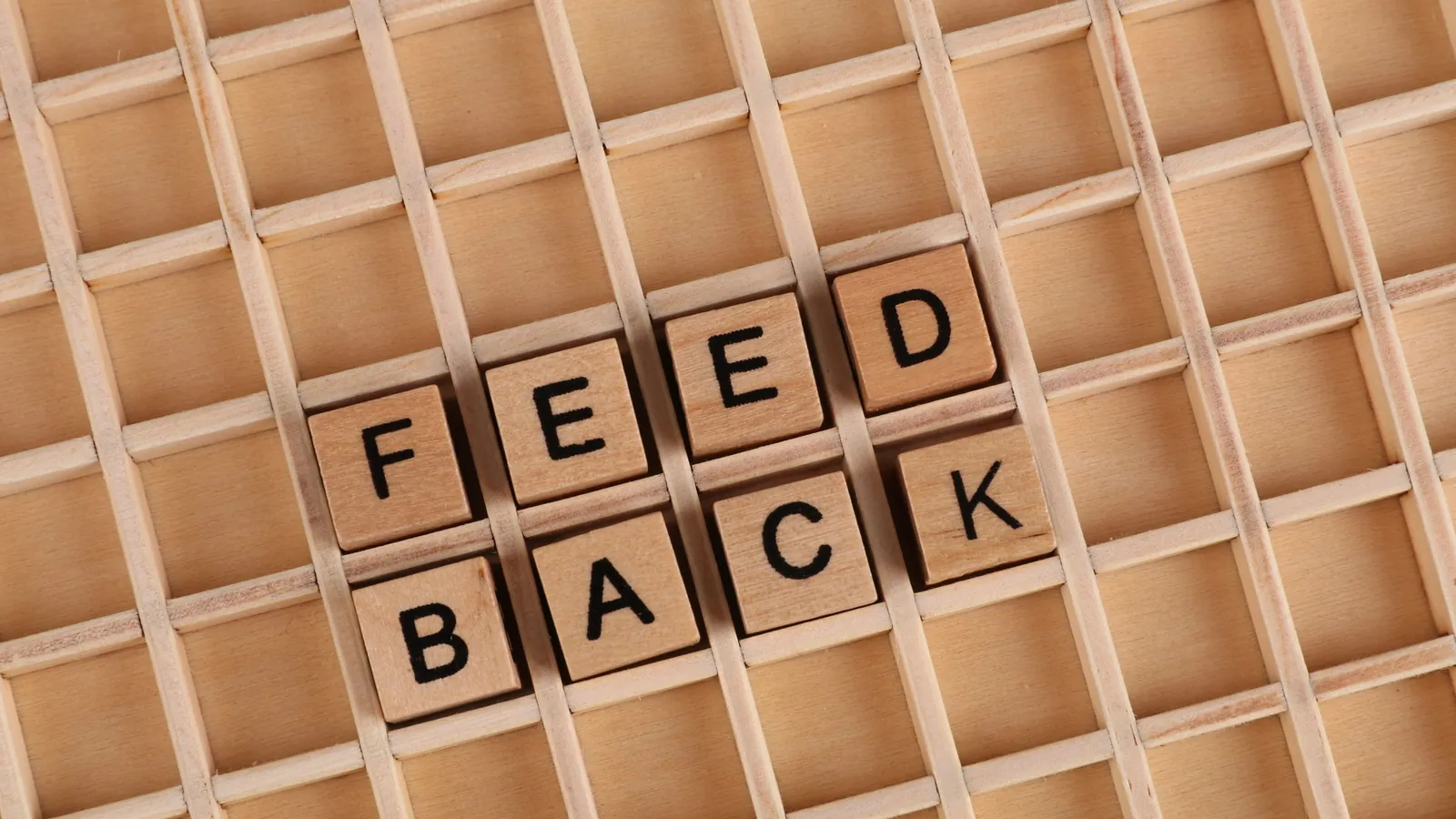 Wooden letter cubes spelling Feedback on a wooden grid